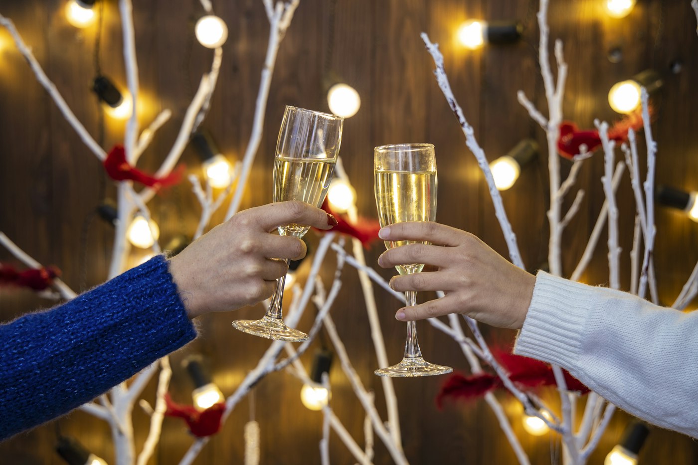 Two glasses raised in a festive toast in front of twinkling lights