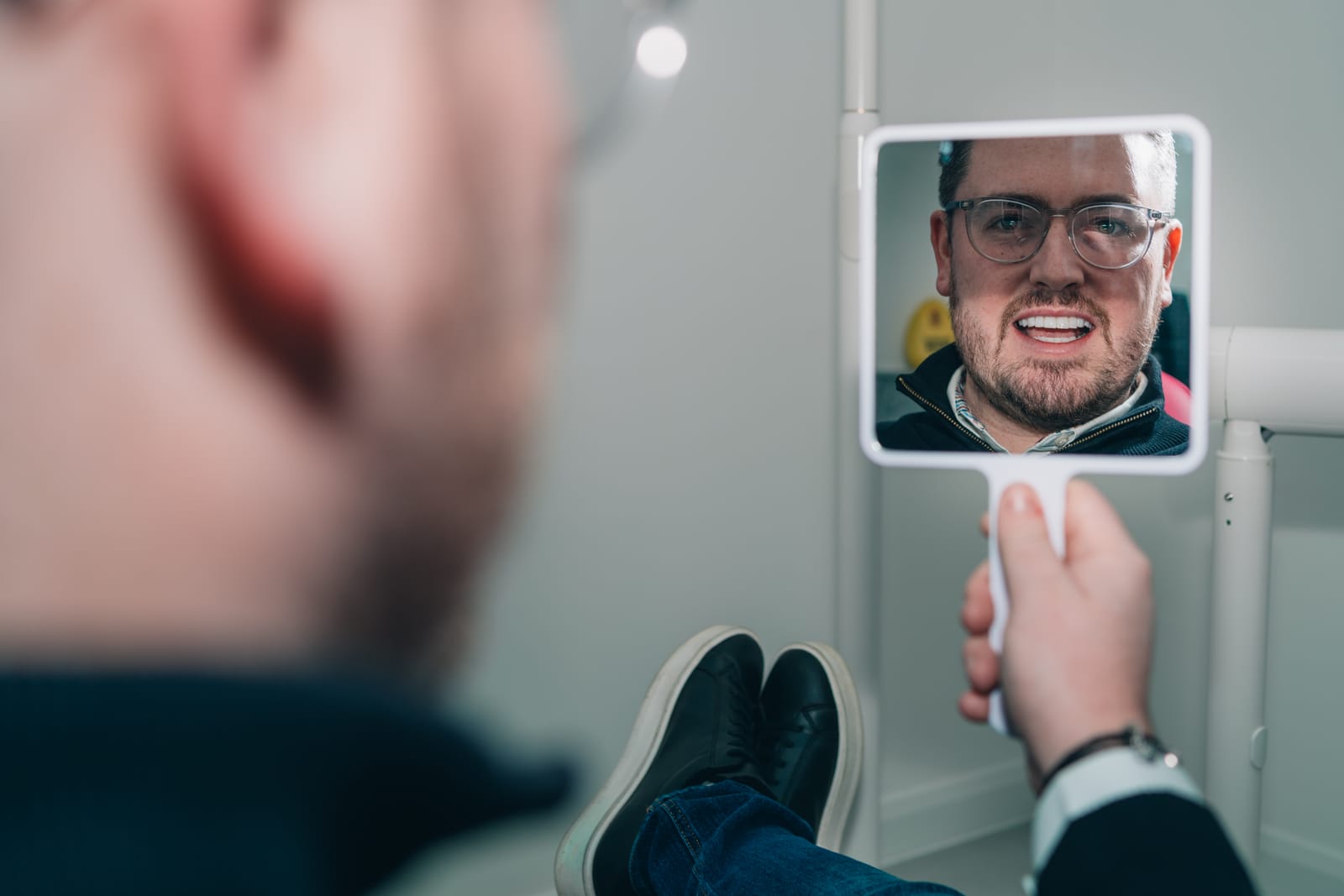 Patient checking his new smile in a hand mirror